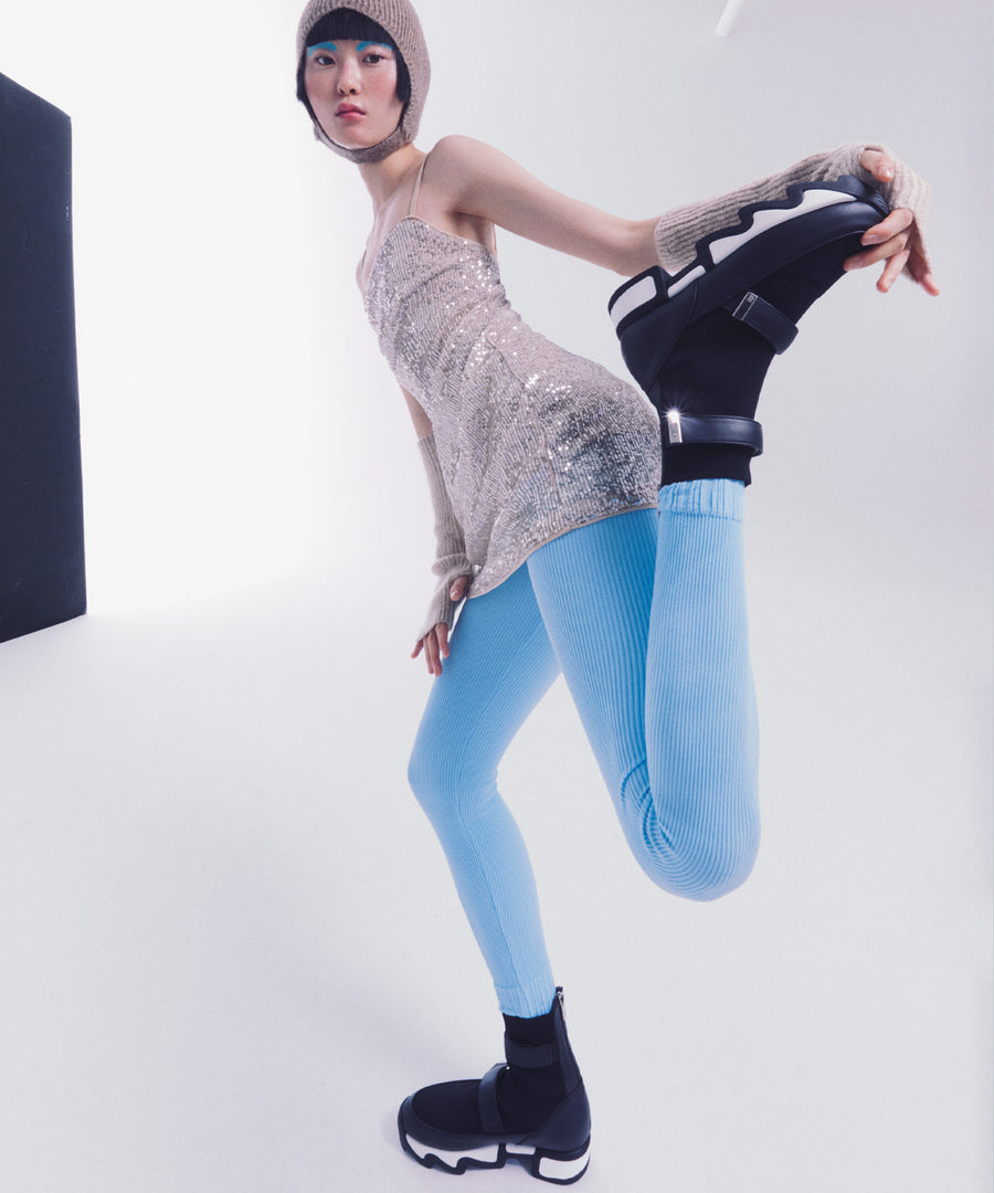 Model wearing VES Black Outline High Top Sneaker with ivory sequinned knit dress and blue knit tights